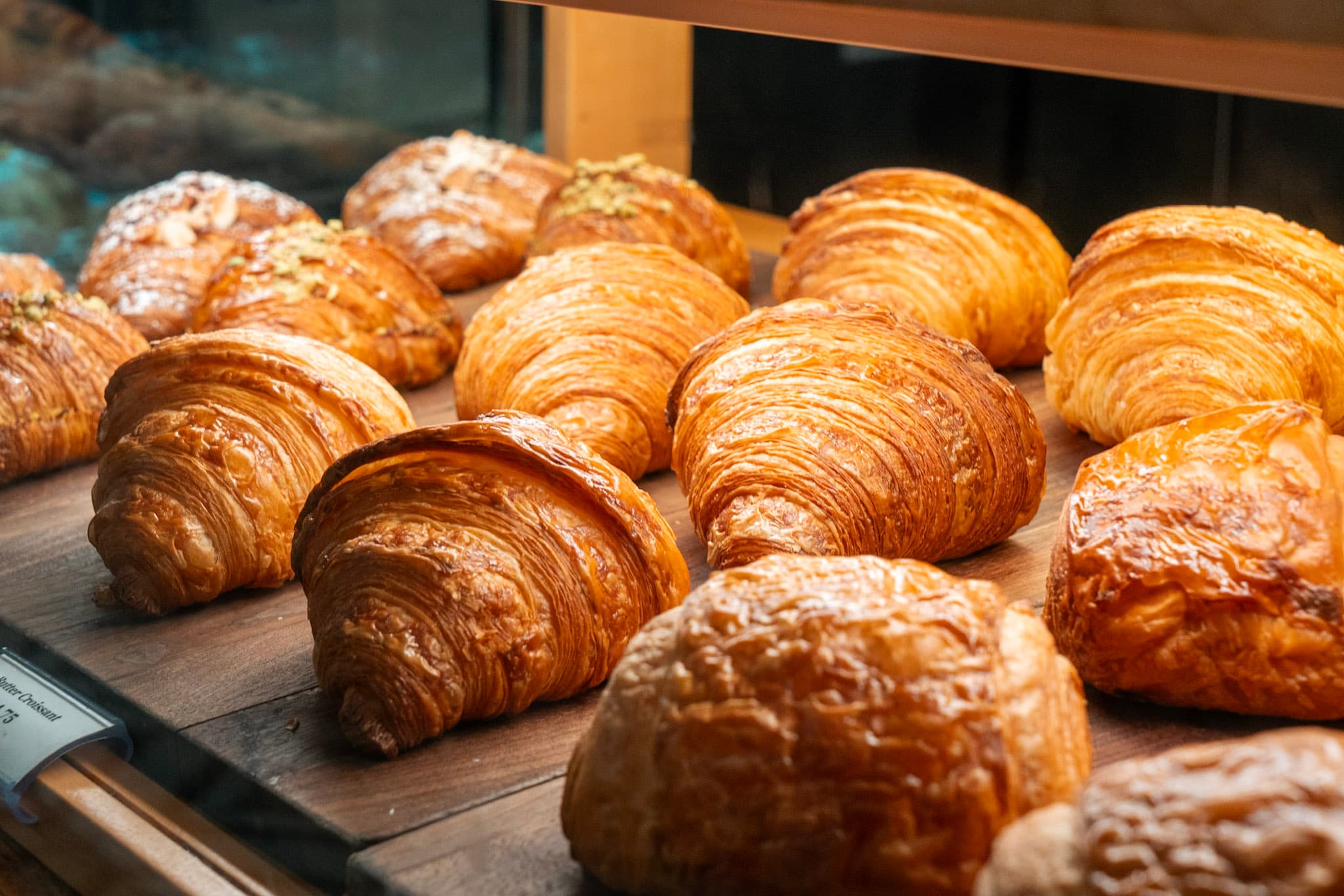Golden butter croissants on wooden boards in bakery display
