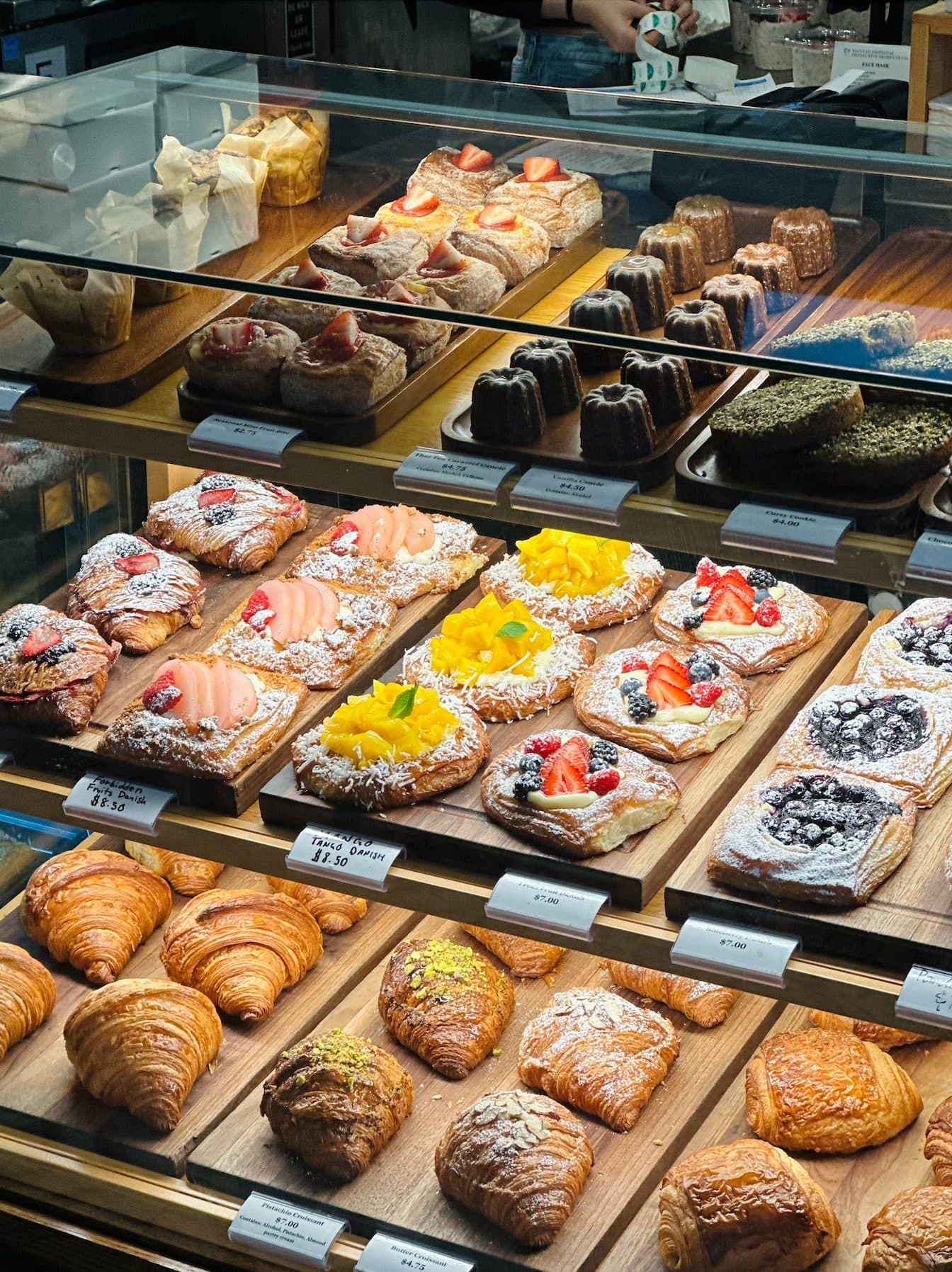 Bakery display case with fruit danishes, canelés, butter croissants and pistachio croissants
